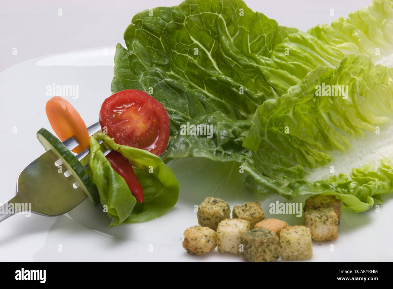 Foglie di lattuga con verdure su una forcella e crostini Foto Stock