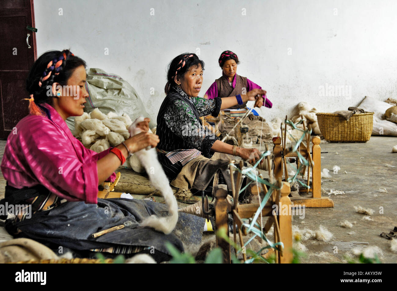 Donne tibetane con un arcaico ruote di filatura, la fabbricazione di tappeti, Shigatse, nel Tibet, Asia Foto Stock