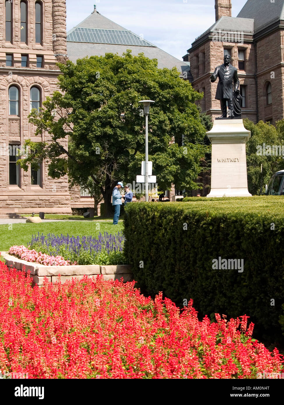 Fiori colorati e una statua di Whitney in Queens Park, in Ontario per gli edifici del Parlamento a Toronto City Centre, Canada Foto Stock