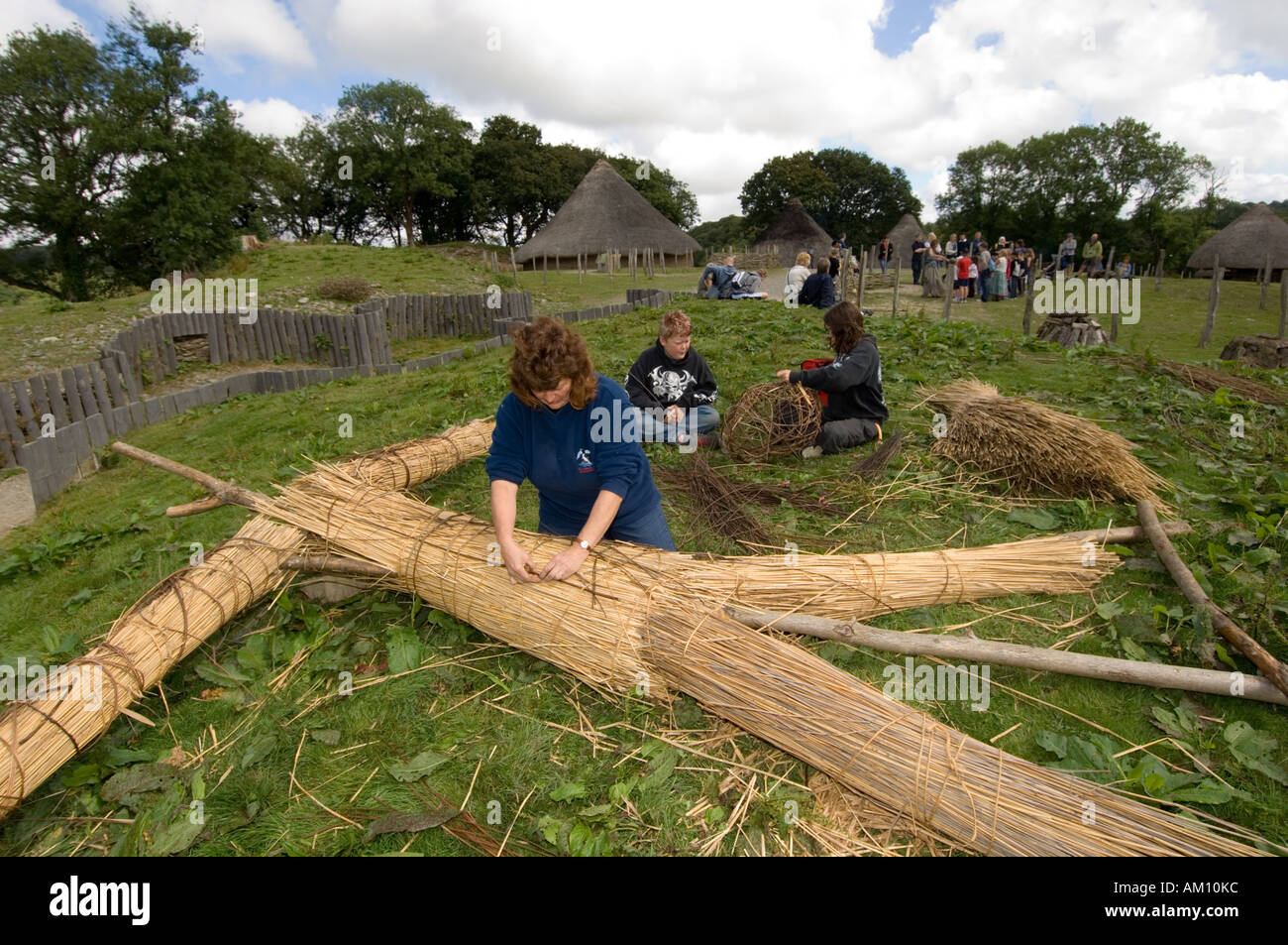 Persone che fanno un uomo di vimini Castell Henllys ricostruito in età di ferro hill fort Pembrokeshire wales Foto Stock