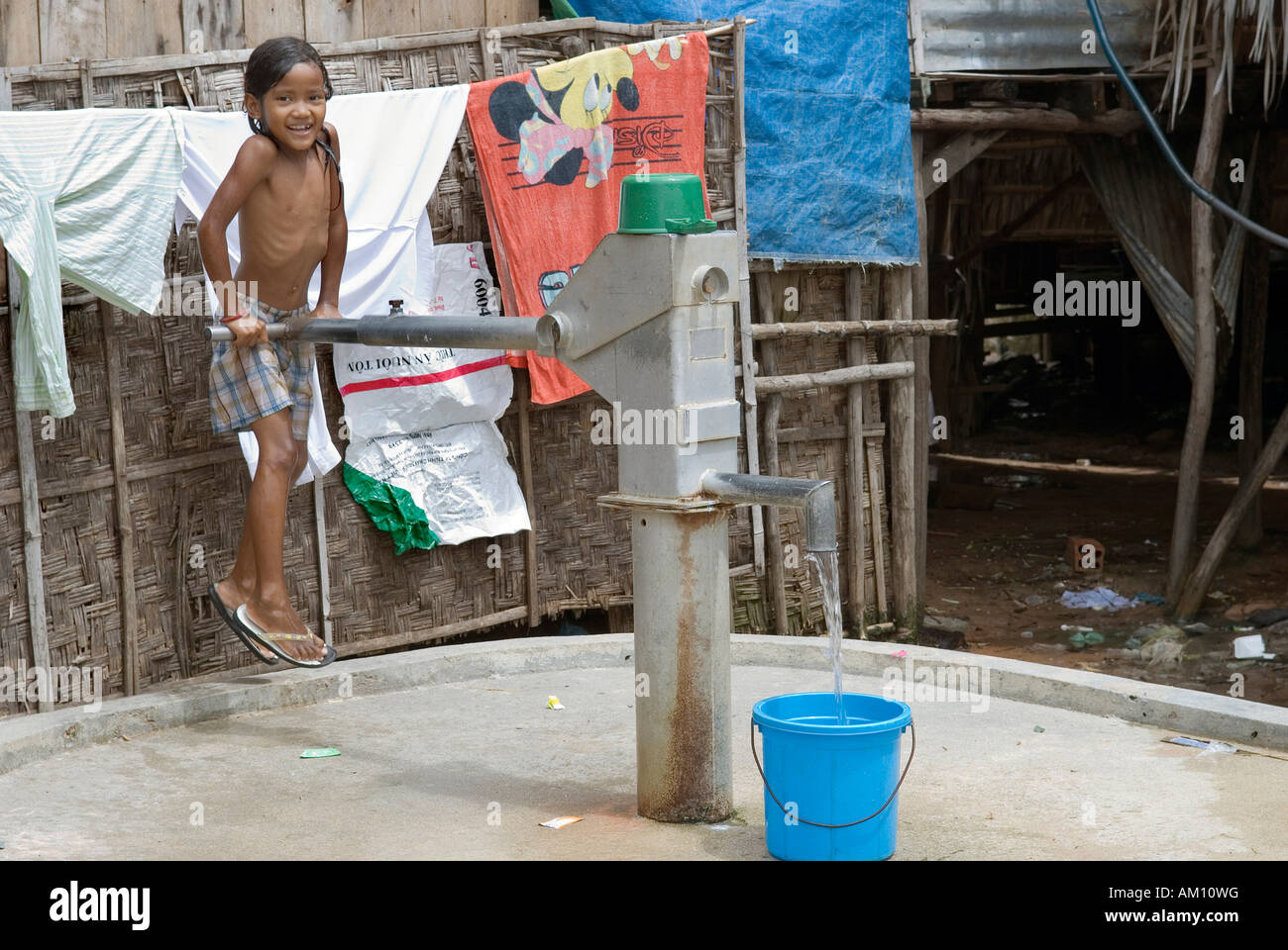 Ragazza il pompaggio di acqua in corrispondenza di un pozzetto, Andong baraccopoli, Phnom Penh Cambogia Foto Stock