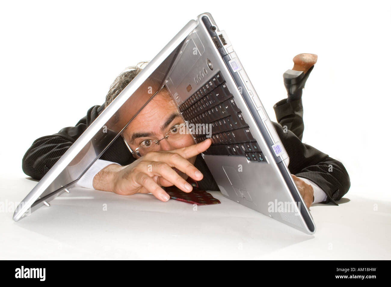 Uomo d'affari che giace dietro un notebook Foto Stock