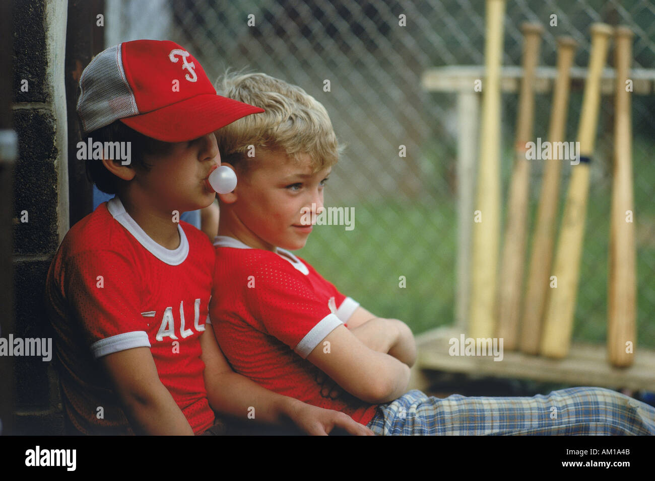 Poco i leghisti seduto con le mazze da baseball chewing bubble gum USA Foto Stock