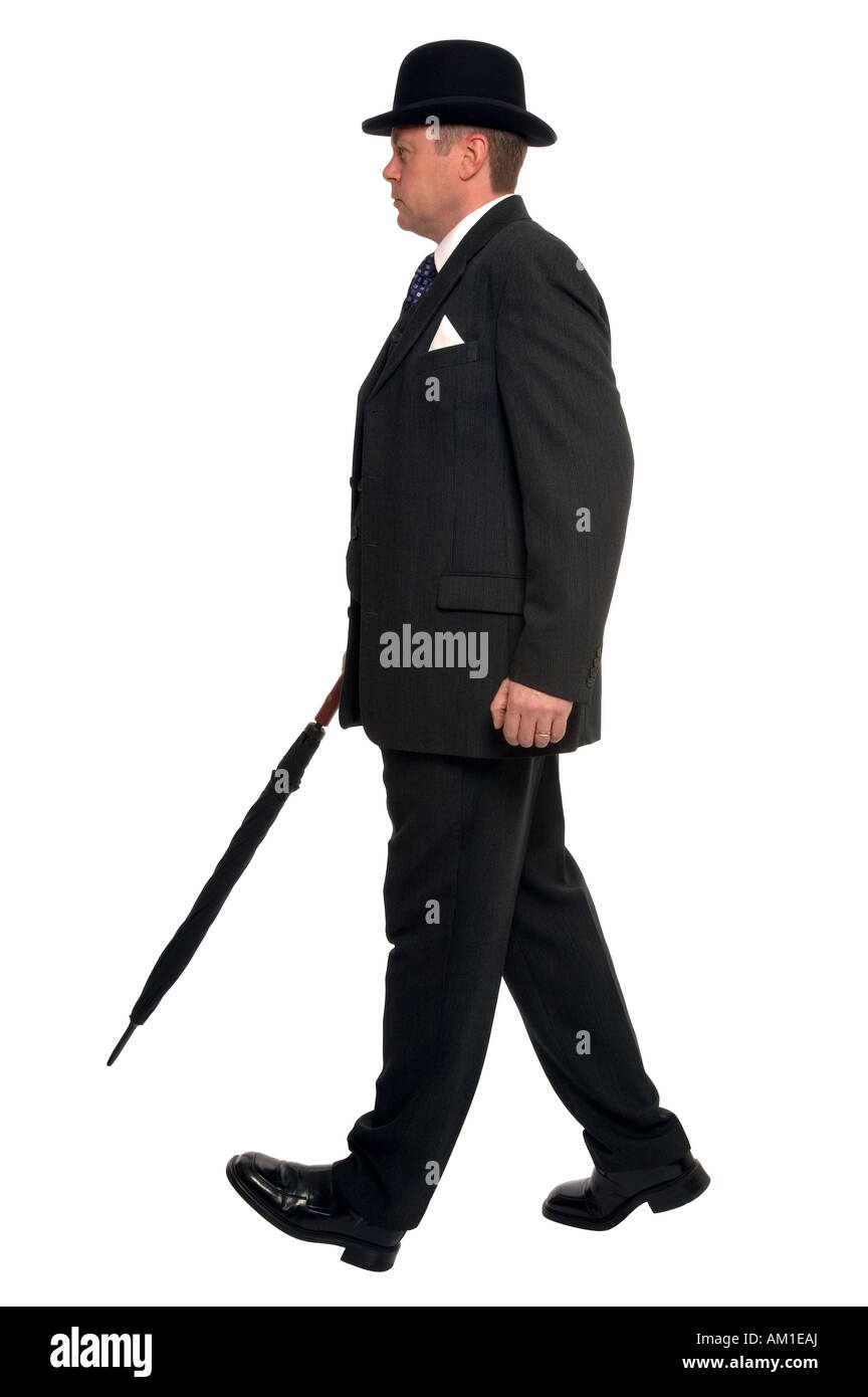 Città imprenditore nel pin tuta a strisce che indossa un cappello bowler e portando un ombrello come egli cammina lungo Foto Stock