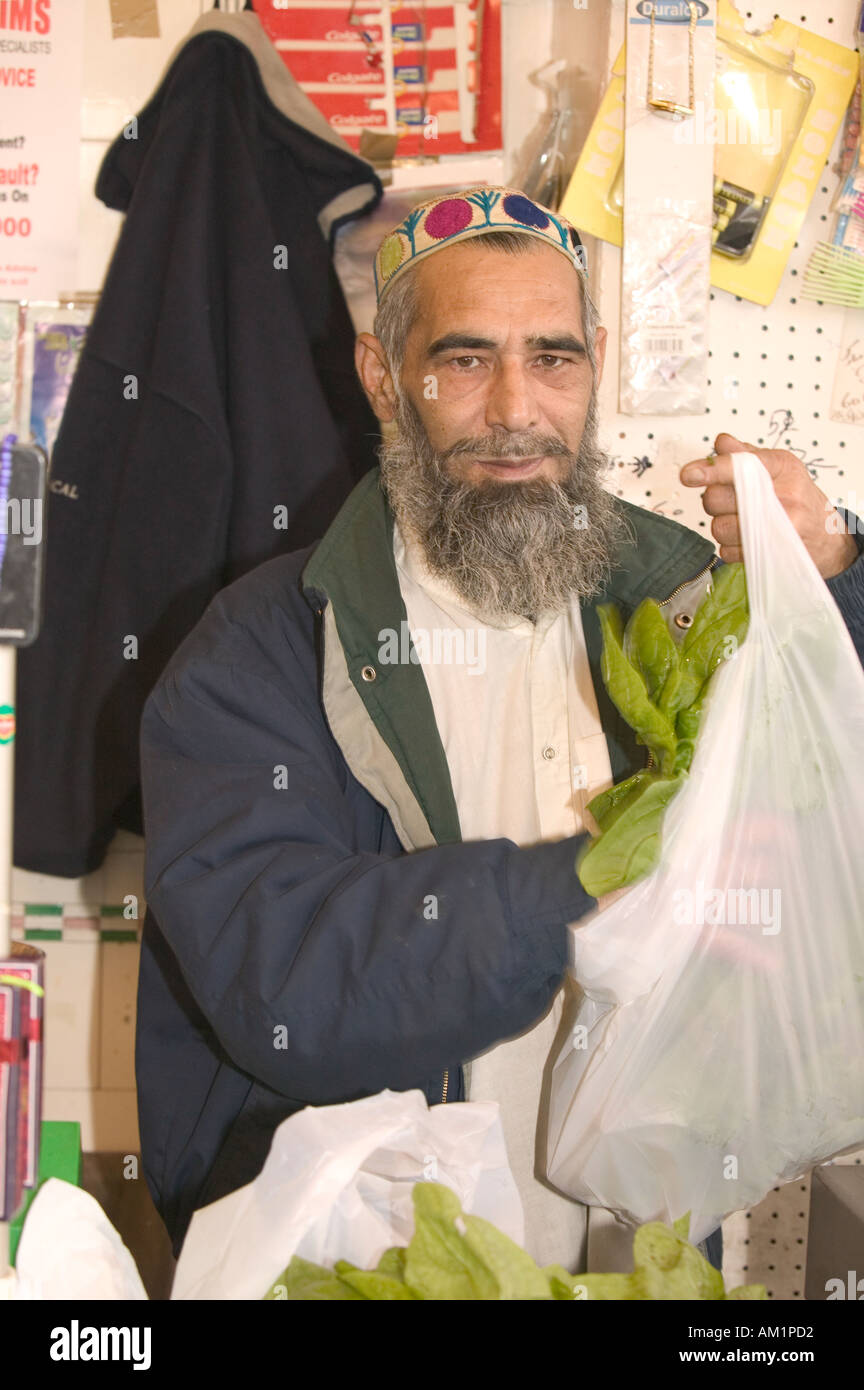 Un pakistano negoziante in un negozio asiatico a Burnley Lancashire Foto Stock