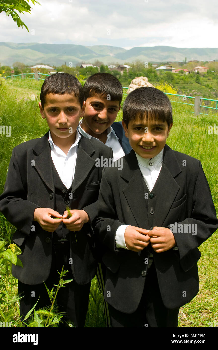 ARMENIA Garni tre età scolare i ragazzi nel buio tre pezzo adatta per stare insieme all'aperto erba alta montagna e case Foto Stock