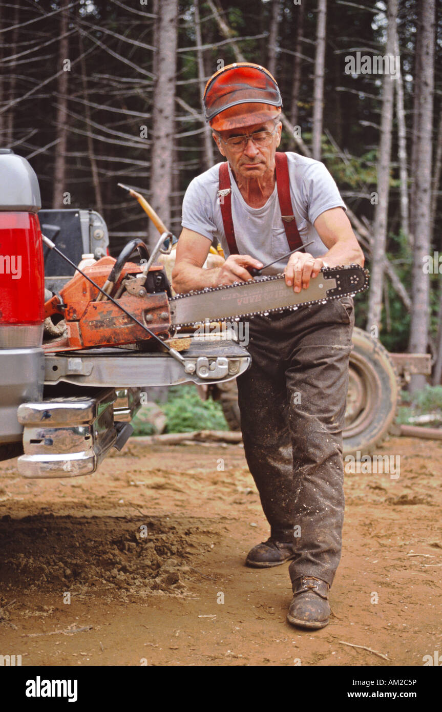 Francese canadese lumberjack affina la sua chainsaw nei boschi del nord del New Hampshire USA Foto Stock