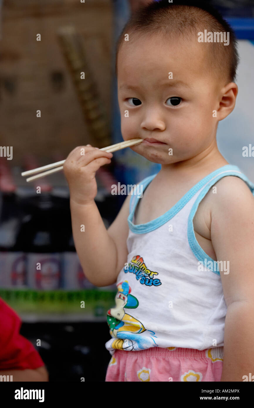 Bimbi cinesi di mangiare con bacchette in hutong di Pechino CINA