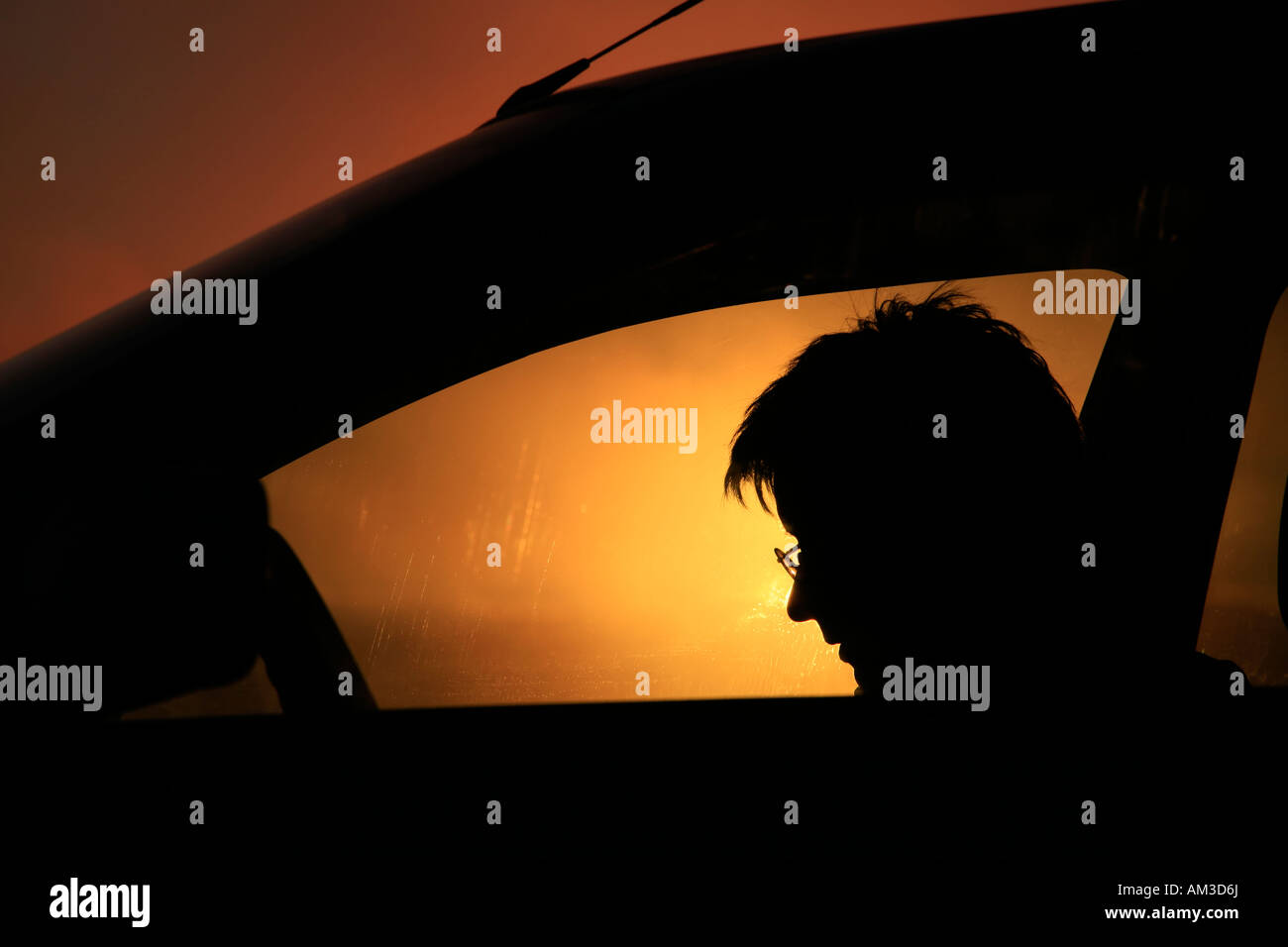 Donna che legge un libro in una vettura; silhouette contro il drammatico tramonto in Islanda Foto Stock