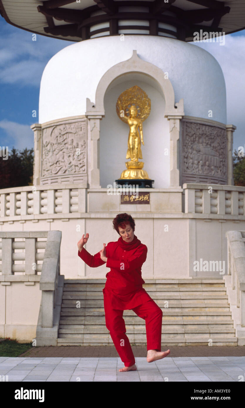 Carol Smith insegnante di Yoga facendo Surya Namaskar Sun Salutations davanti al Milton Keynes buddista Pagoda di pace Foto Stock