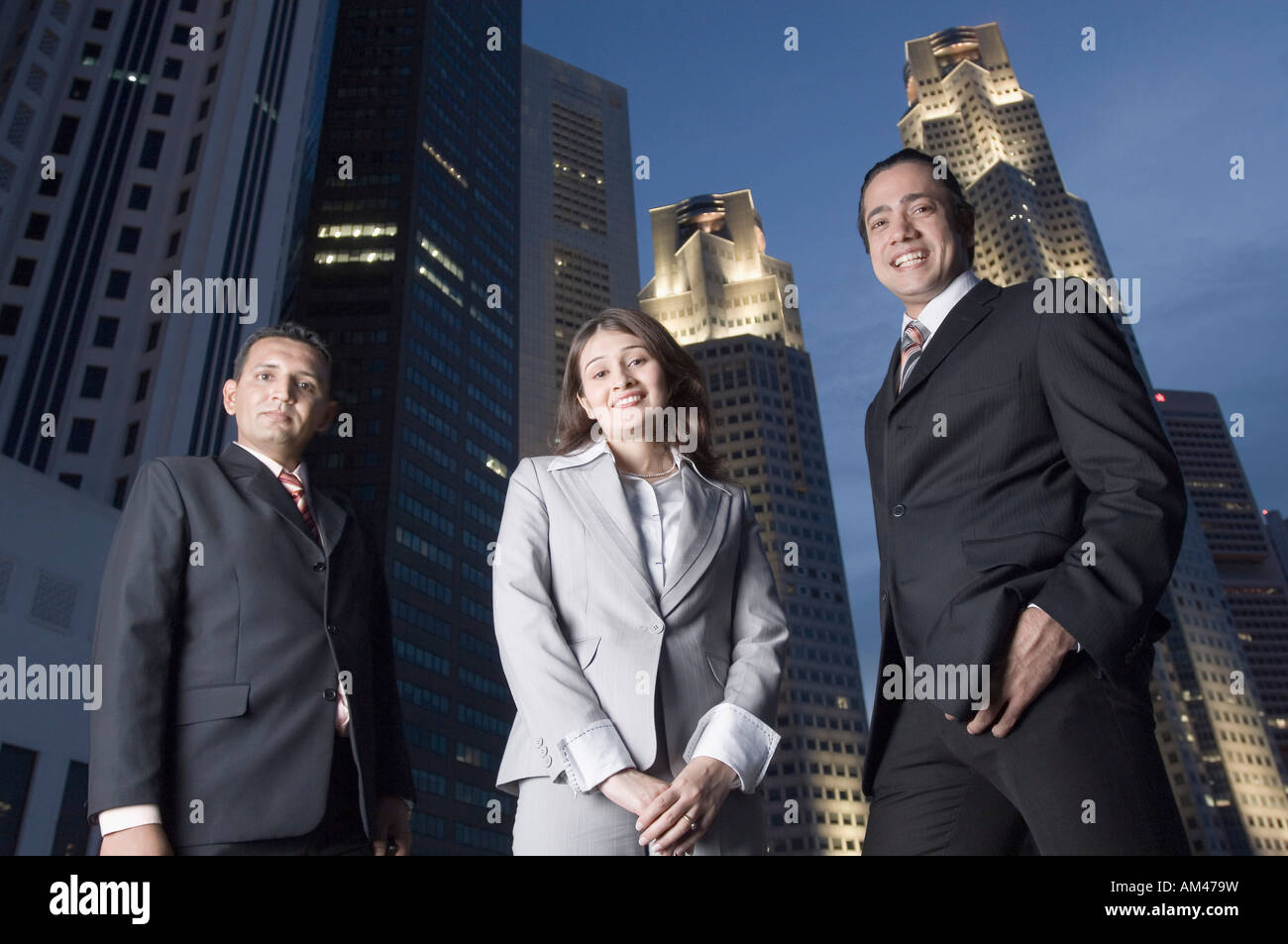 Ritratto di due imprenditori in piedi con una imprenditrice con grattacieli in background, Singapore Foto Stock
