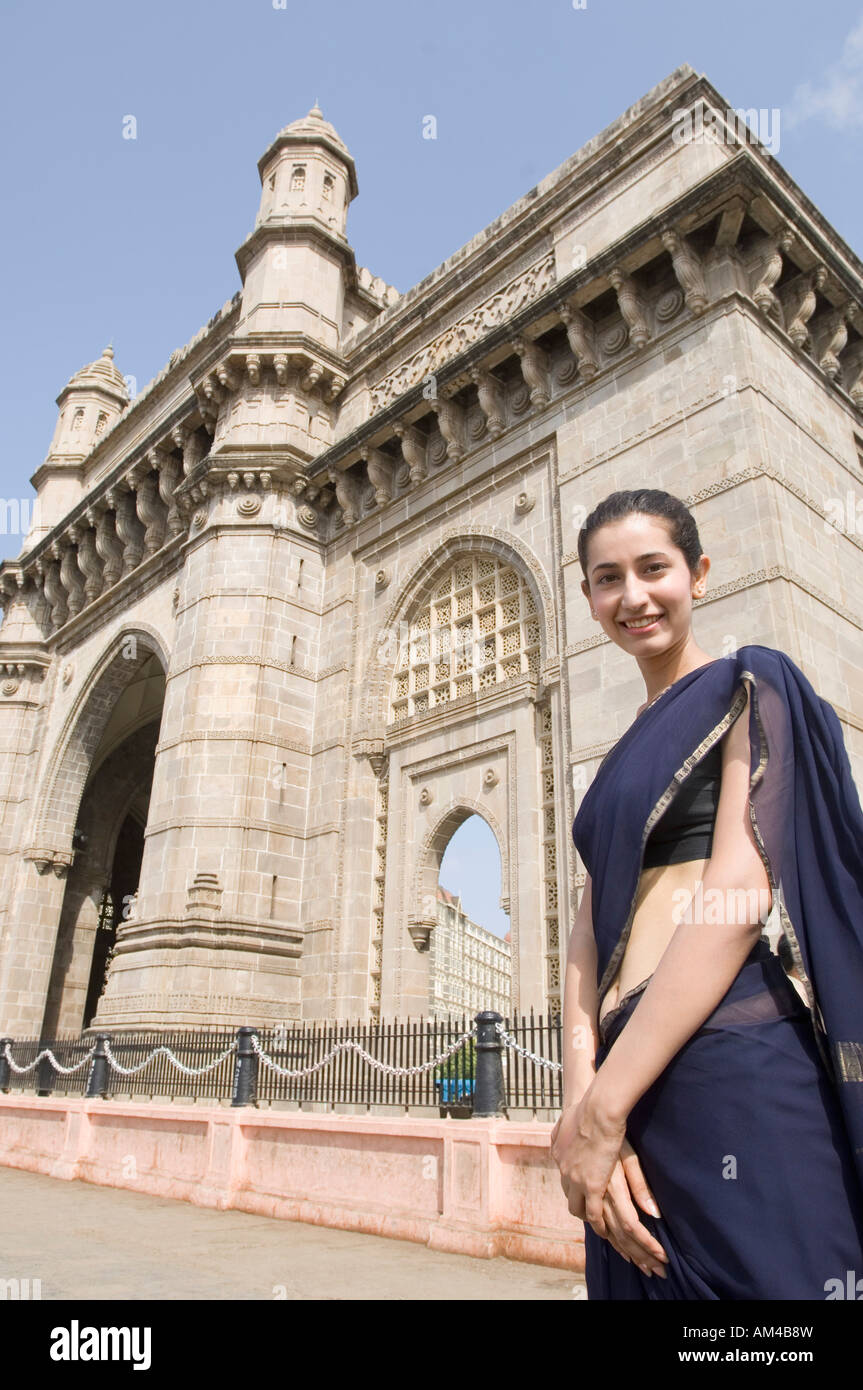 Ritratto di una giovane donna in piedi di fronte ad un monumento, Gateway of India, Mumbai, Maharashtra, India Foto Stock