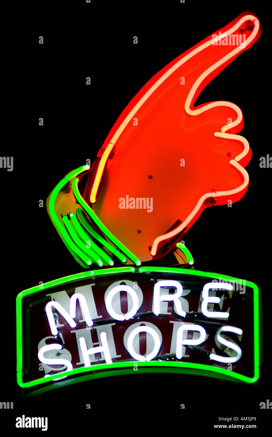 Insegna al neon più negozi con una mano verso destra e verso l'alto. Isolato su nero. Foto Stock