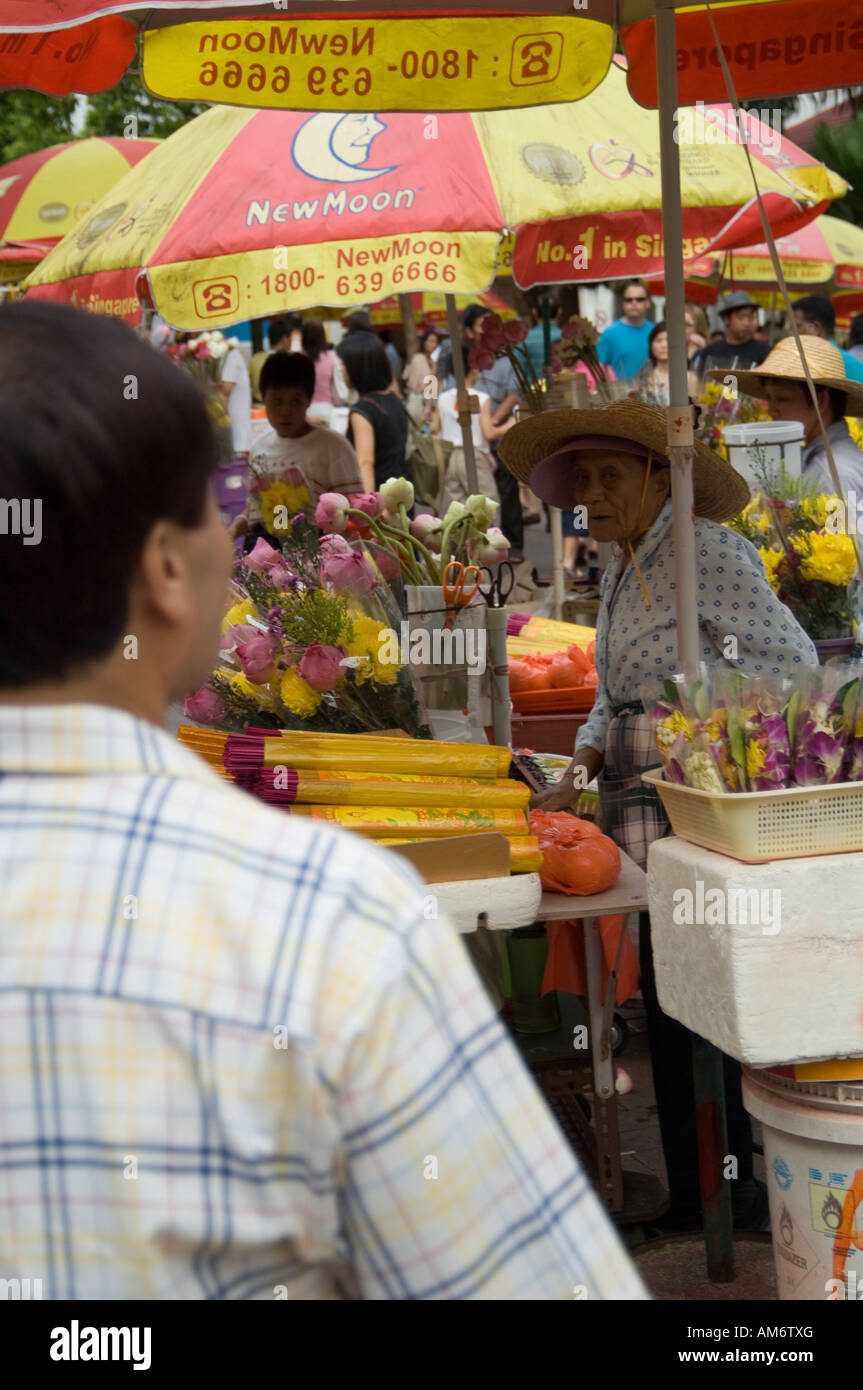 Il vecchio donna asiatica che vendono fiori al di fuori di un tempio buddista in Singapore Foto Stock