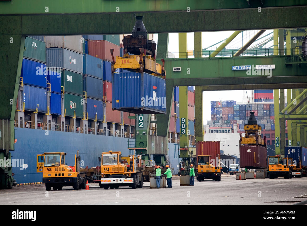 Contenitori impilati nel porto di Singapore vengono caricati dai camion e macchinari Foto Stock