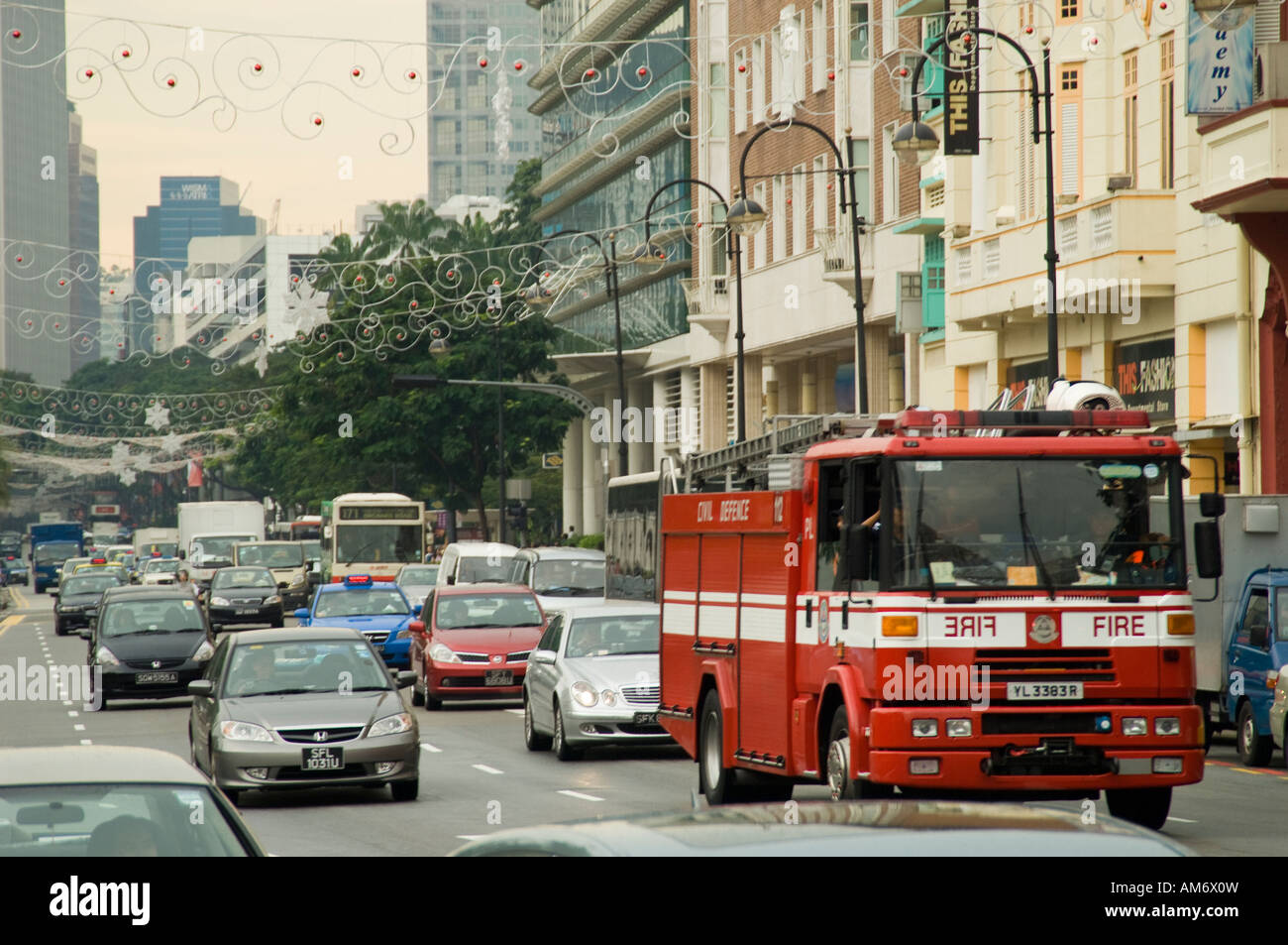 Del traffico su una strada nel centro cittadino di Singapore pieno di autovetture e di un motore Fire Foto Stock