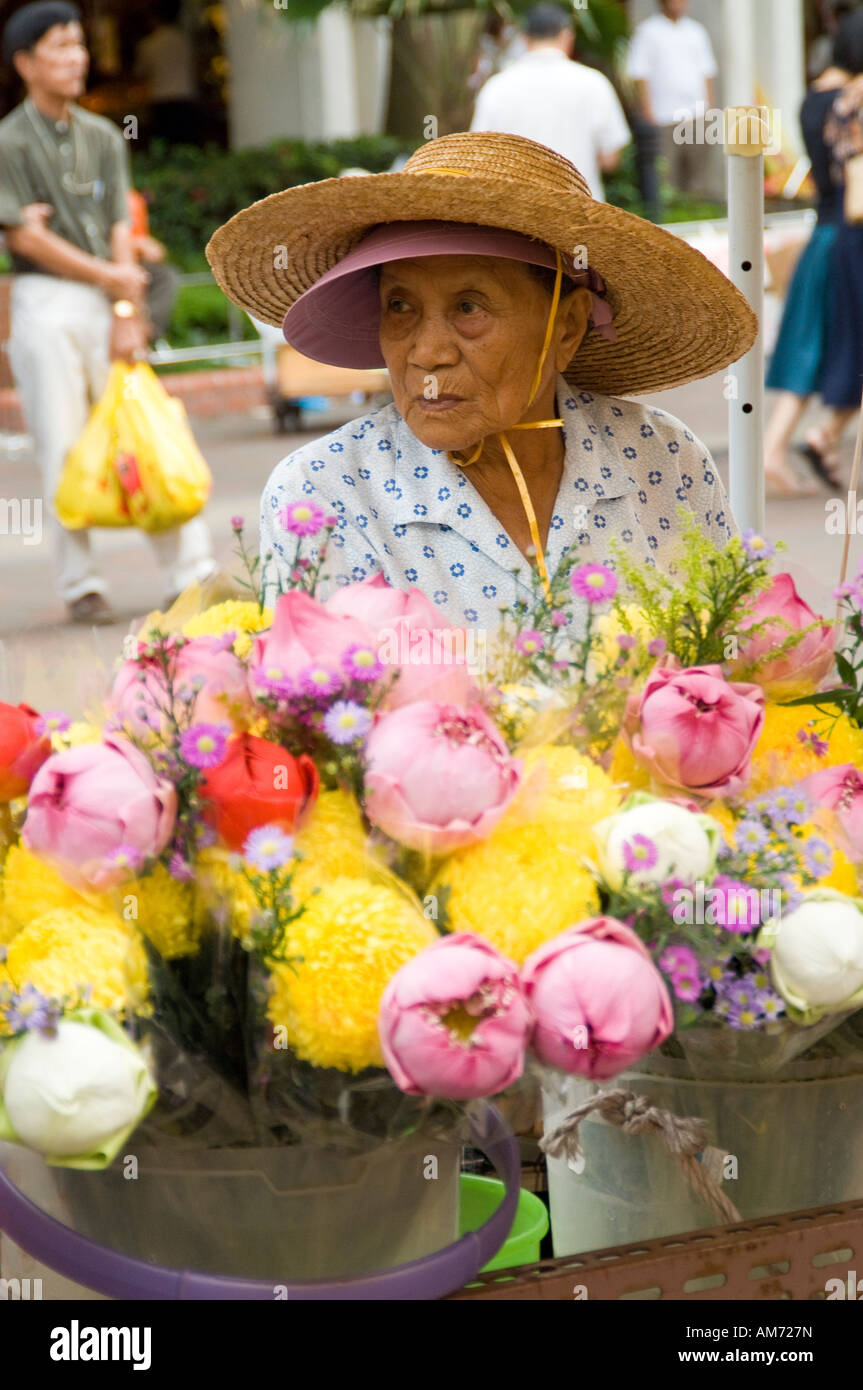 Il vecchio donna asiatica che vendono fiori al di fuori di un tempio buddista in Singapore Foto Stock