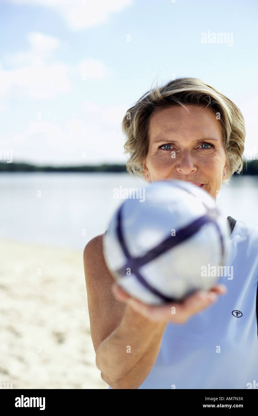 Bestager 60+ con pallavolo sulla spiaggia Foto Stock