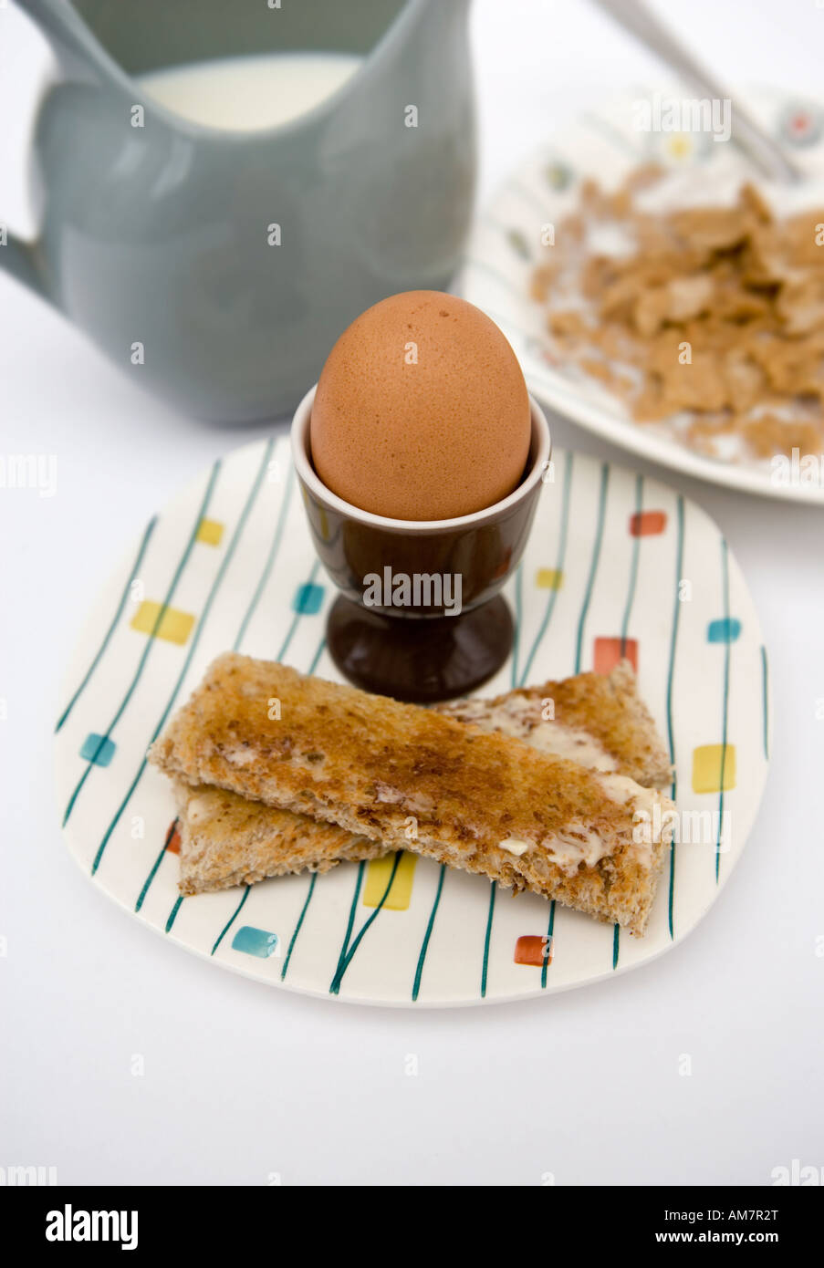 Tavolo per la colazione compresa un uovo sodo e toast cornflakes e una caraffa di latte Foto Stock