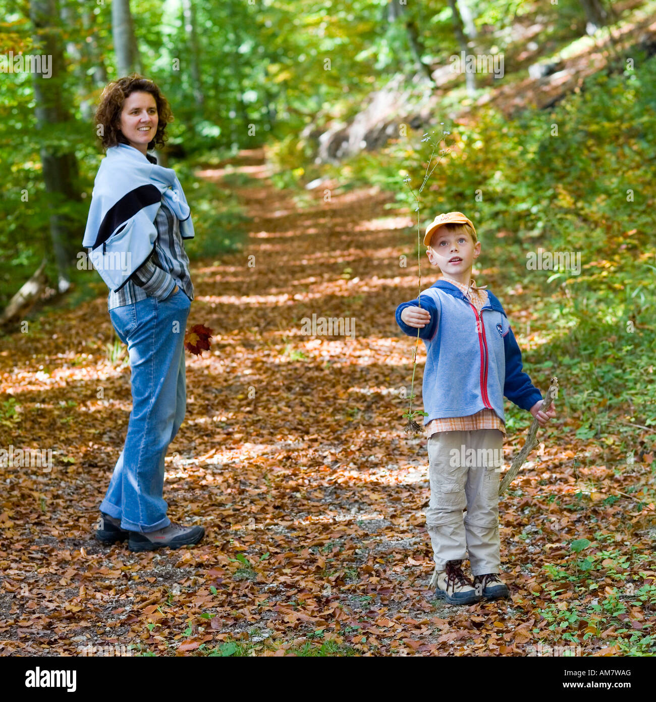 Un bambino di cinque anni, ragazzo e sua madre facendo una passeggiata in un bosco autunnale Foto Stock