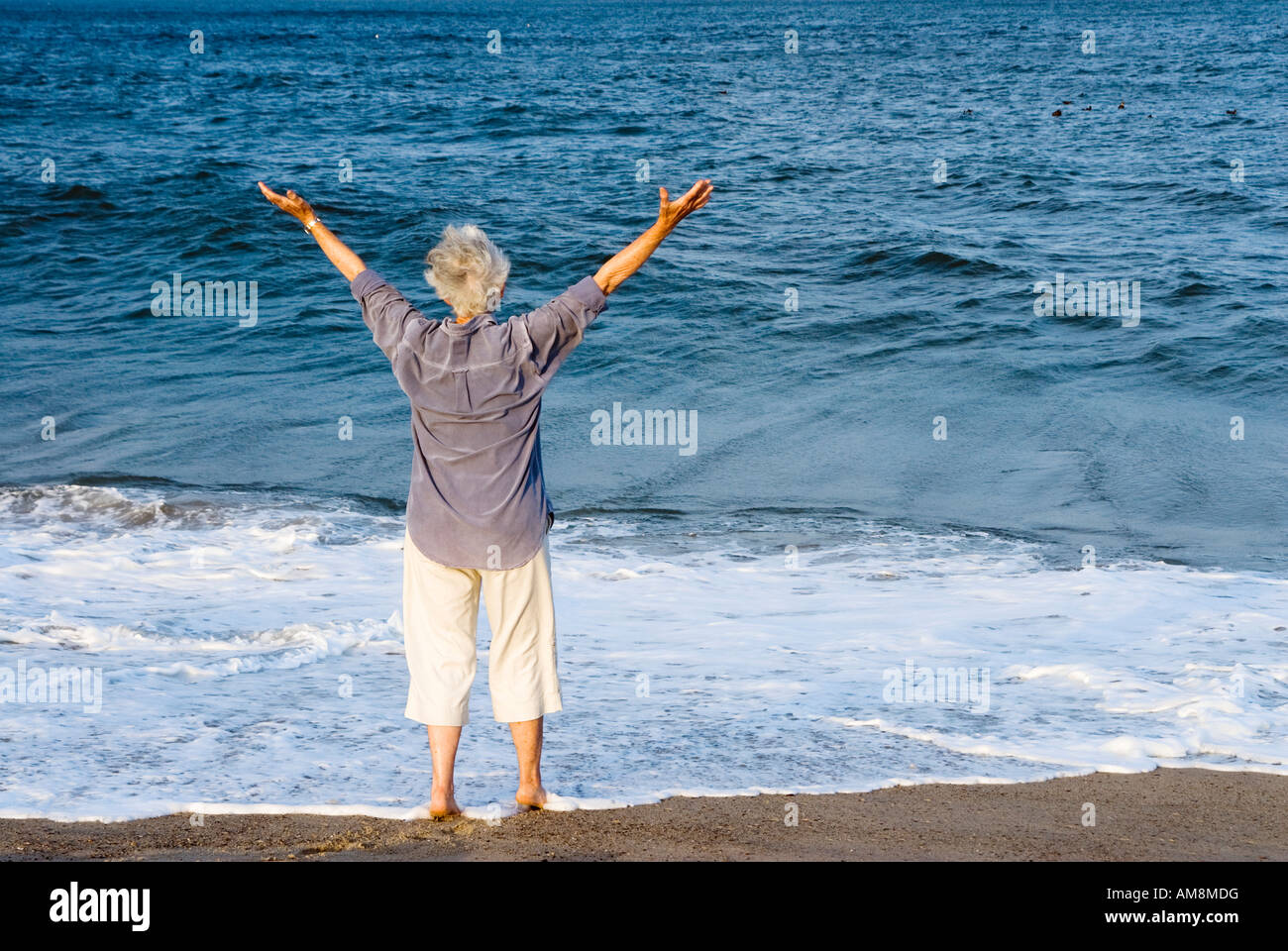Senior donna accoglie una nuova giornata in spiaggia Nauset Beach Cape Cod MA Foto Stock