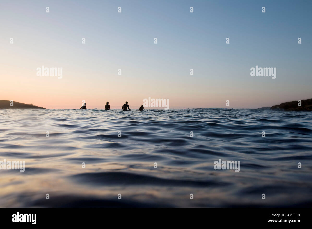 Quattro persone sedute su tavole da surf in acqua. Foto Stock