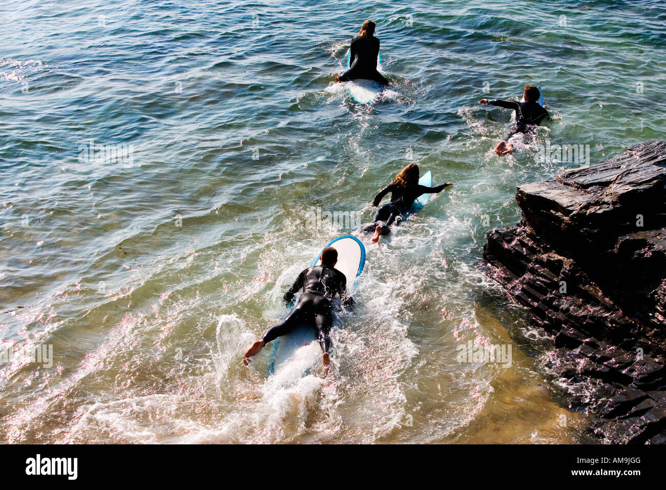 Quattro persone su tavole da surf in acqua. Foto Stock