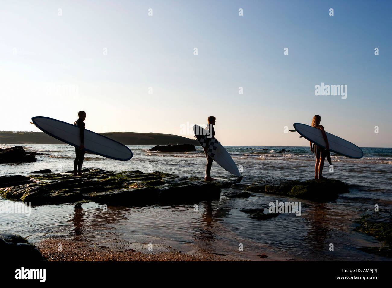 Tre persone che trattengono le tavole da surf in piedi su rocce di grandi dimensioni. Foto Stock