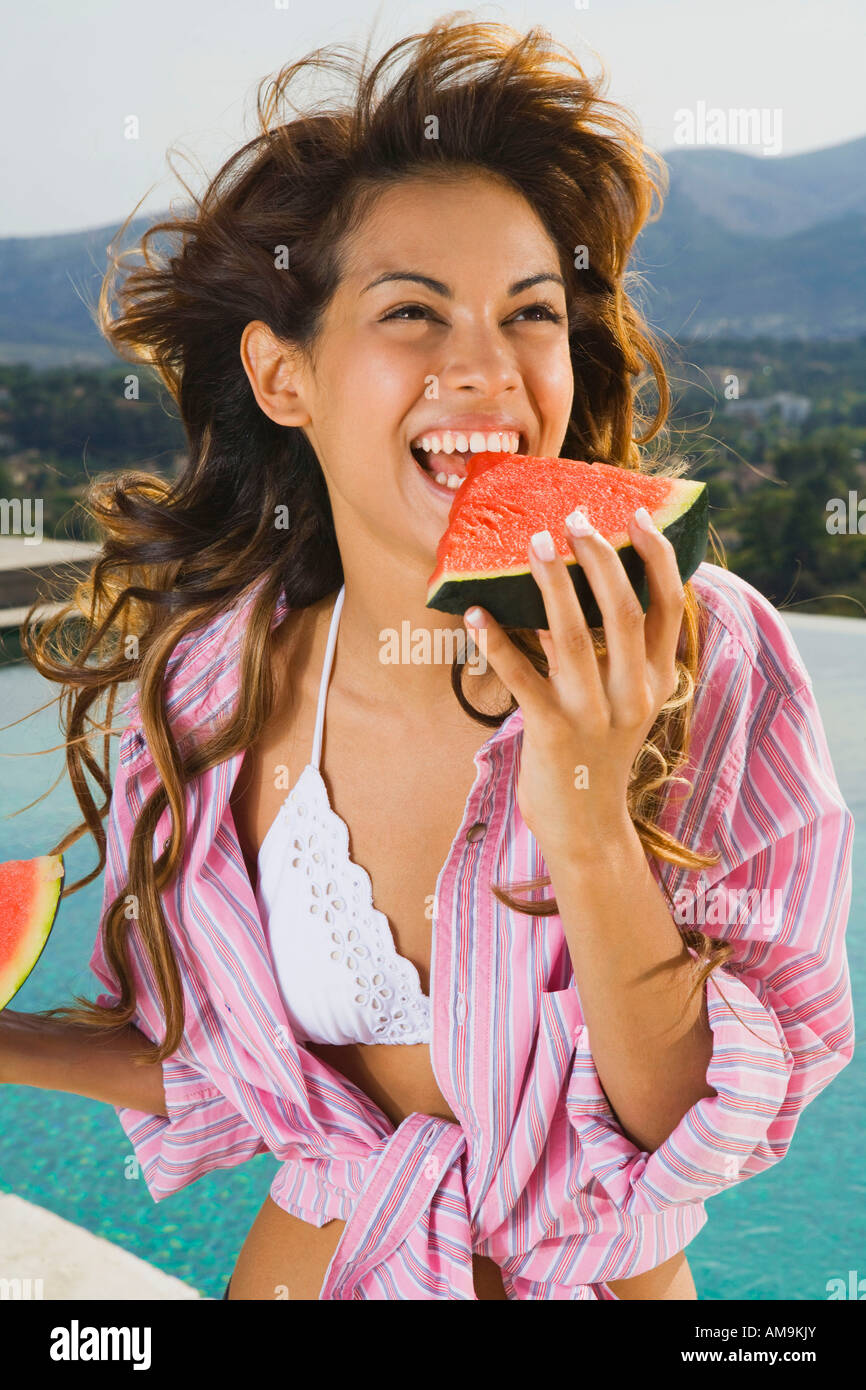 Donna energica con sorriso mangia anguria da piscina all'esterno. Foto Stock