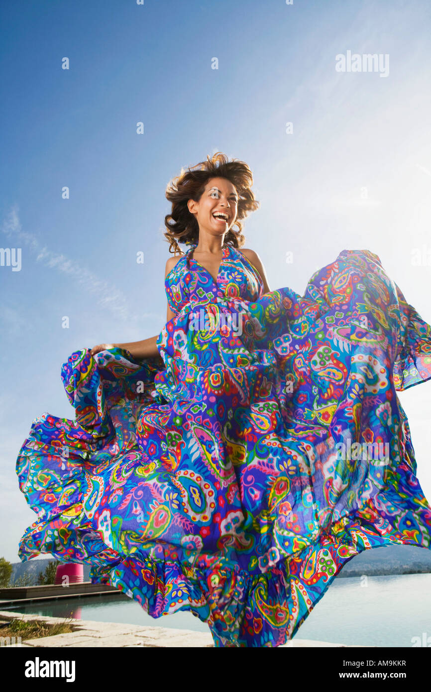 Dynamic bellezza donna ridendo all'aperto in un colorato lungo abiti estivi. Foto Stock