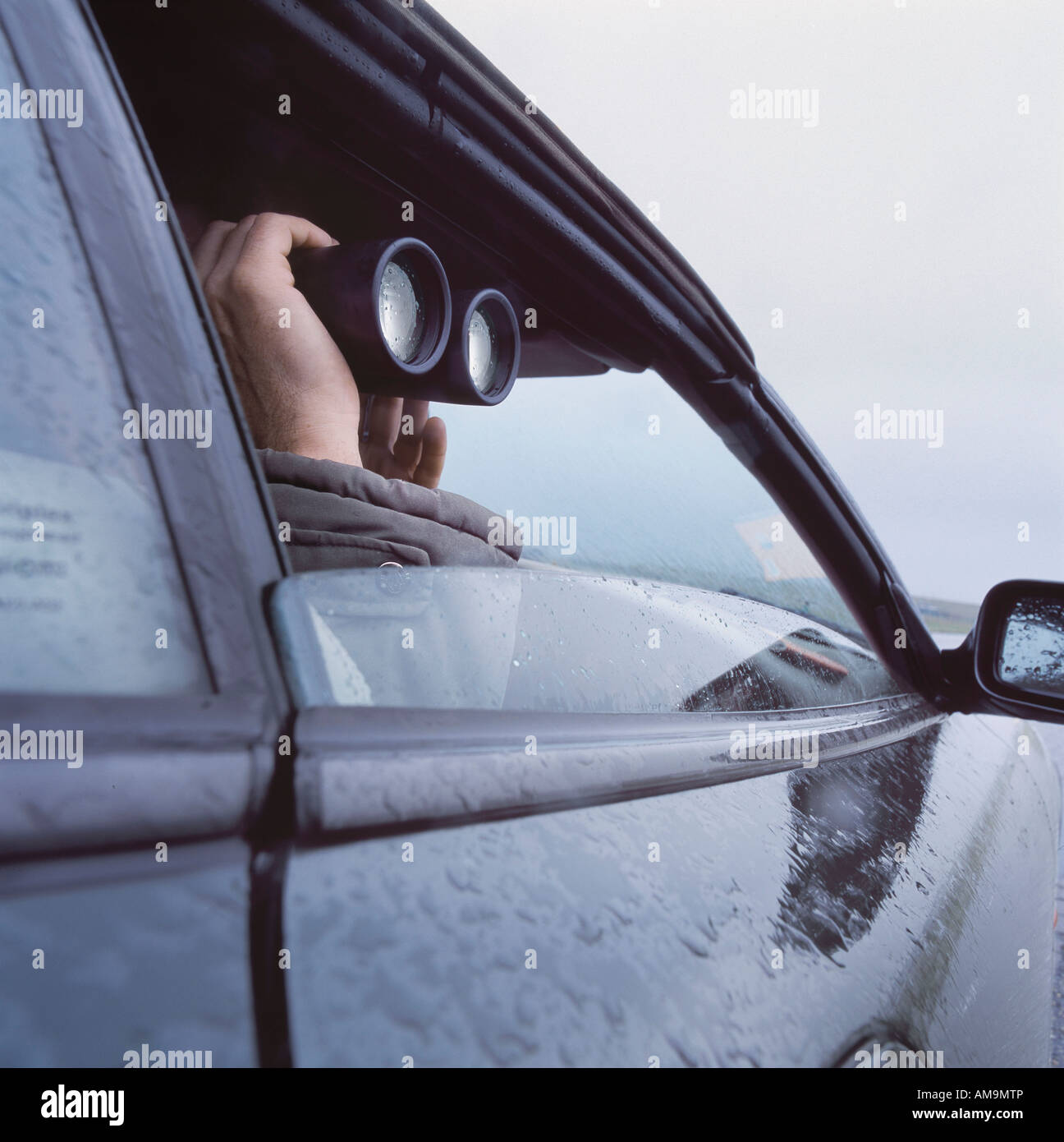 L'uomo con il binocolo spiata attraverso la finestra auto. Foto Stock