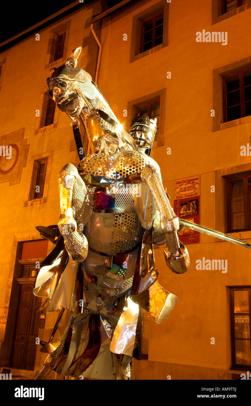 Un tempo di notte colpo di una scultura di un cavaliere in armatura scintillante in piazza Place d'Armes nella cittadina francese di Briancon Foto Stock