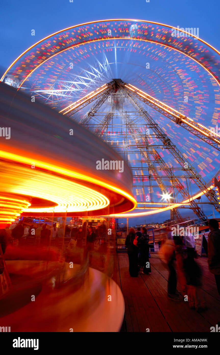 Ruota panoramica Ferris & giostra sul molo centrale di notte a girare intorno con movimento sfocate Blackpool Lancashire England Regno Unito Europa Foto Stock