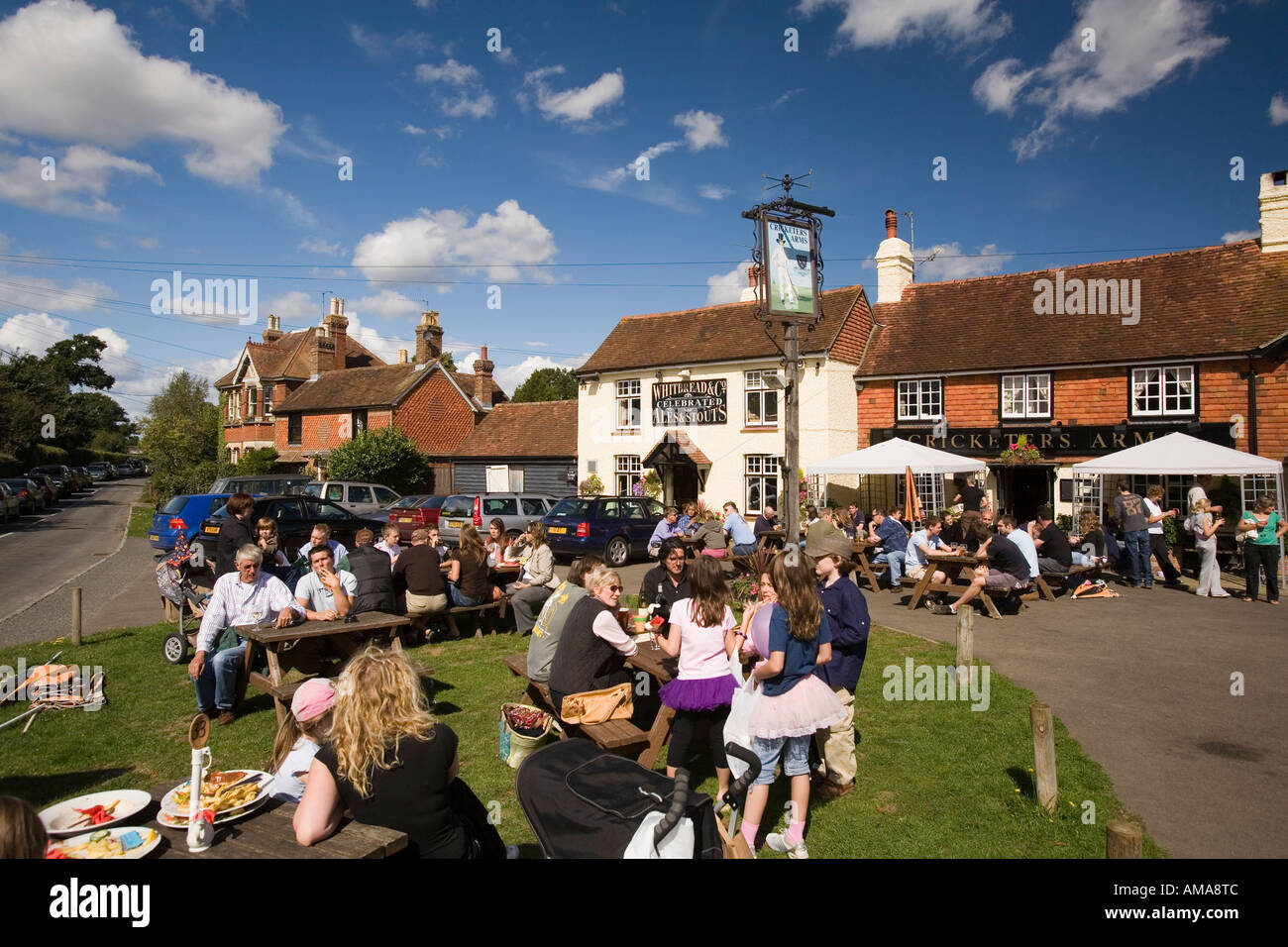 Regno Unito West Sussex Wisborough Green bevitori al di fuori del villaggio Il Cricketers Pub nella luce del sole Foto Stock