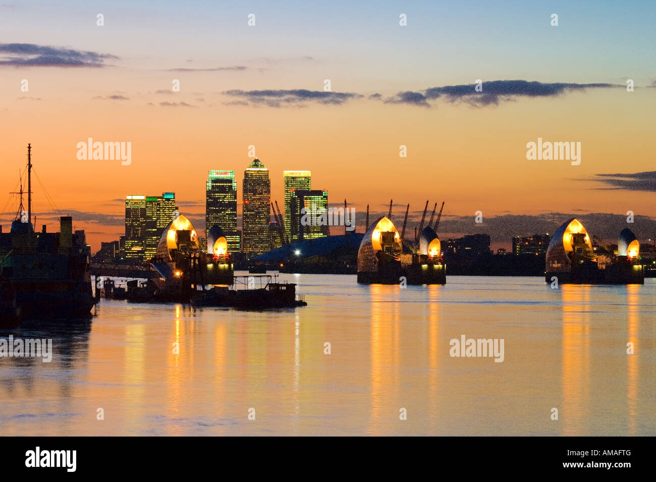 Thames Barrier al tramonto tramonto in serata con il fiume Tamigi e da canary wharf central business district Londra Inghilterra Regno Unito Europa Foto Stock