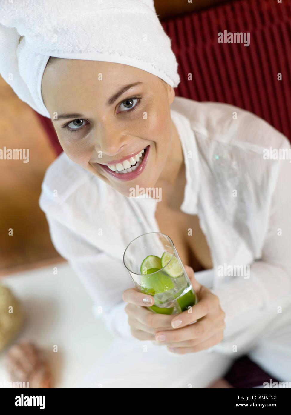 Donna seduta sul cuscino tenendo un bicchiere di acqua di calce, close-up Foto Stock