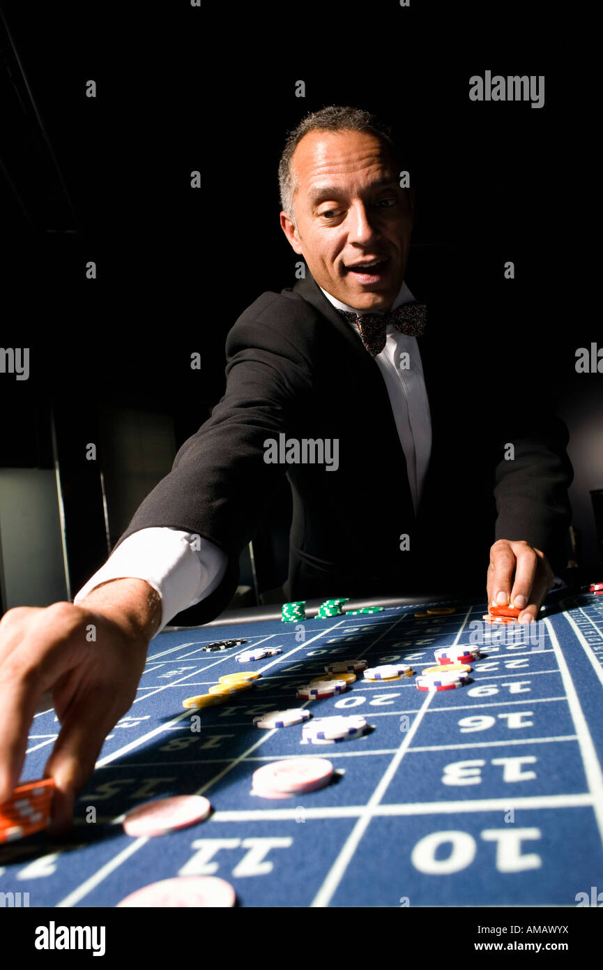 Ben vestito uomo immissione puntata alla roulette tavolo Foto Stock
