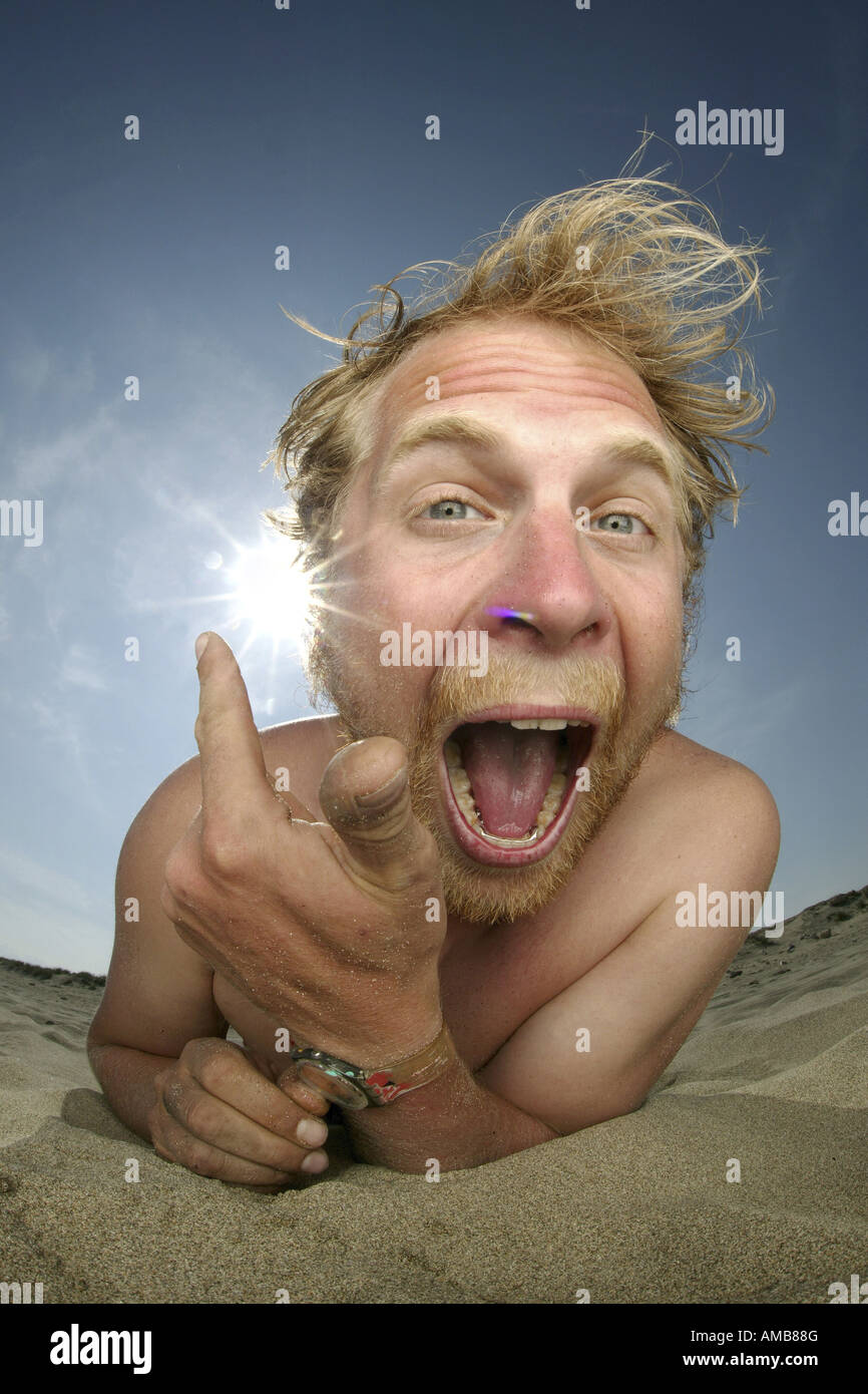 Crazy giovane uomo disteso sulla spiaggia, sole bruciare al suo orecchio Foto Stock