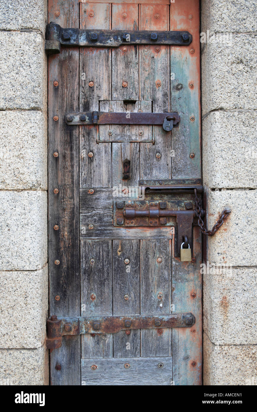 In legno solido porta con cerniere vecchia, bullone e lucchetto insieme alla luce dei blocchi di granito Foto Stock