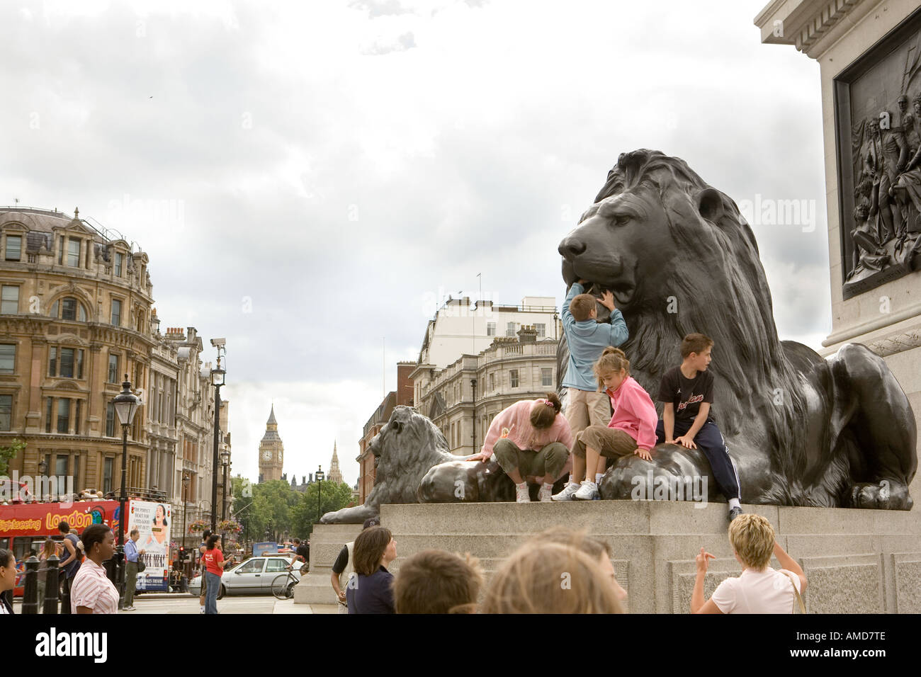I turisti con Nelsons Column Lions in Trafalgar Square a Londra con il Big Ben in background Foto Stock