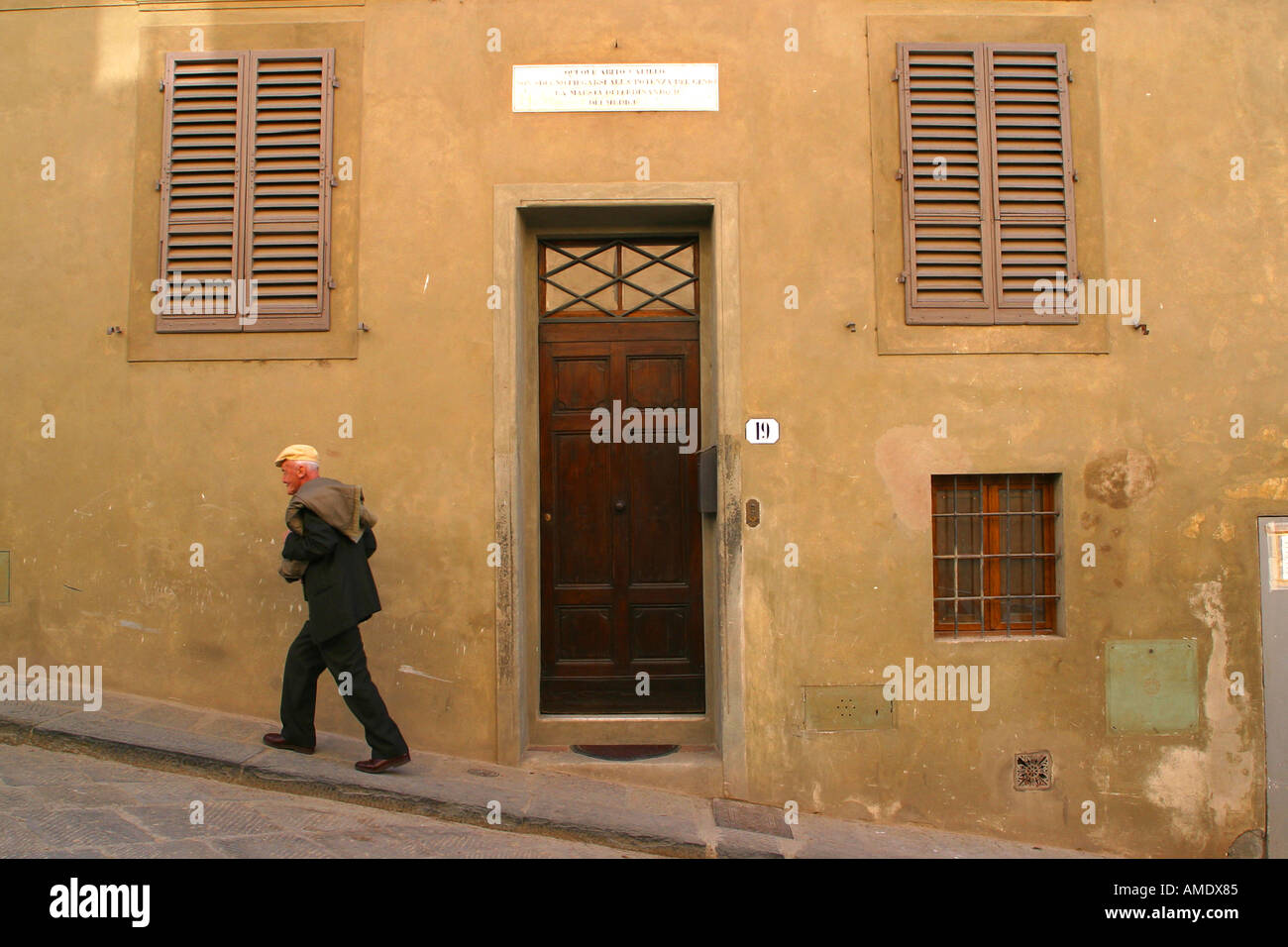 Un vecchio uomo che cammina oltre la porta numero 19 dove Gallileo il matematico vissuto sulla Costa di San Giorgio Firenze Italia Foto Stock