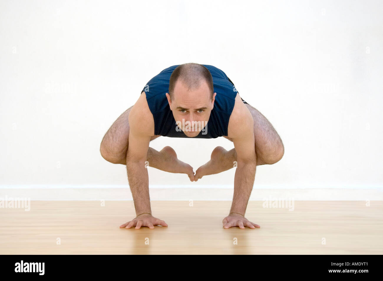 Uomo in equilibrio su le sue mani in una difficile posizione di yoga Foto Stock