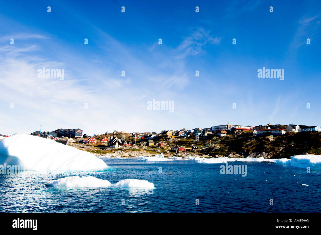 Iceberg di fronte alla città di Ilulissat Colurful case baia di Disko Ilulissat o Jacobshavn Groenlandia Foto Stock