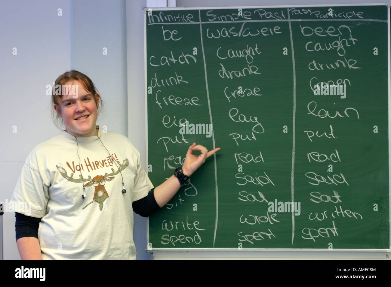 Una ragazza ha scritto i verbi irregolari sulla scheda a scuola Foto Stock
