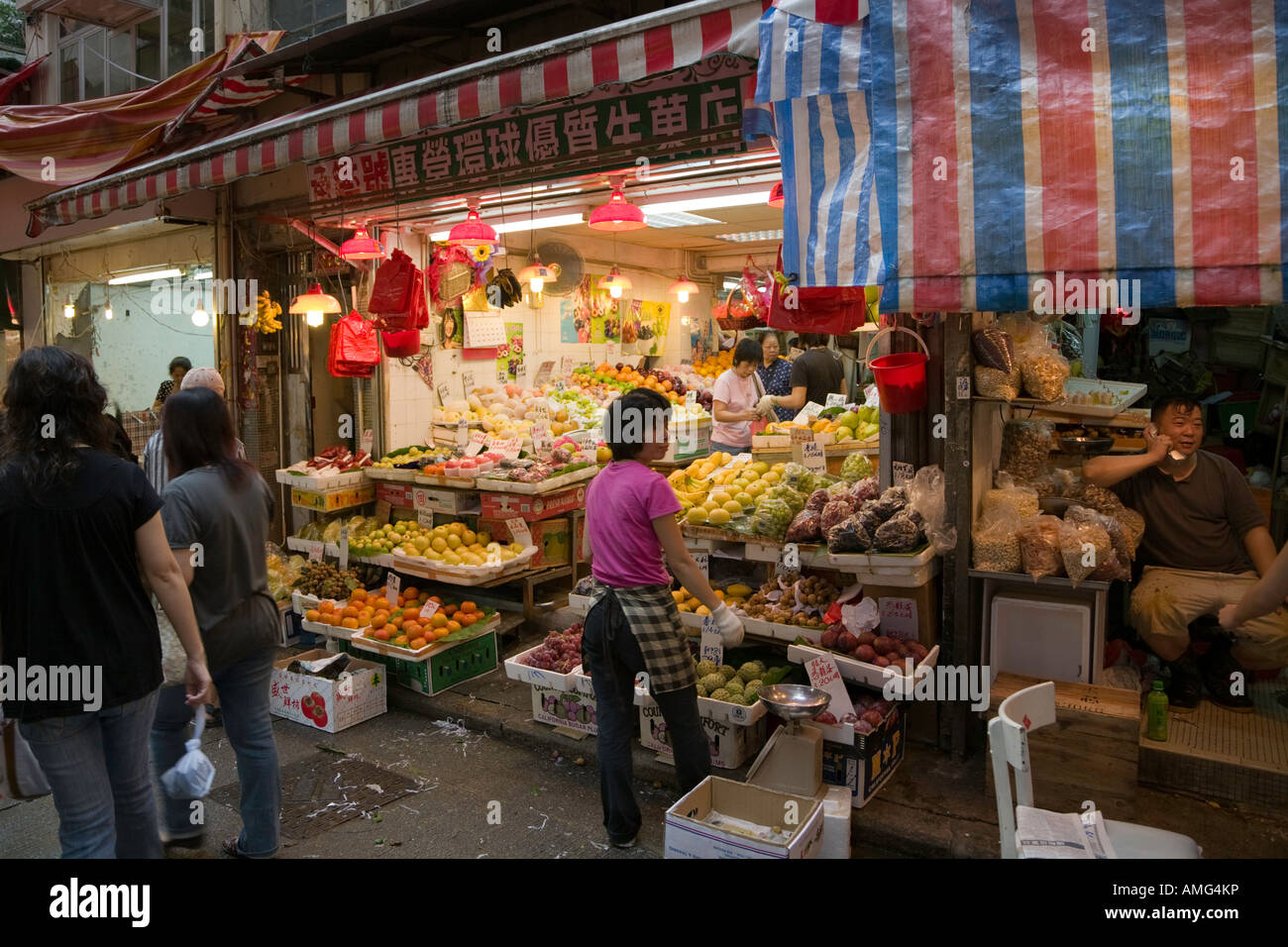 Una donna che regola il display di frutta e verdure fresche in un negozio a Wan Chai market Hong Kong Foto Stock