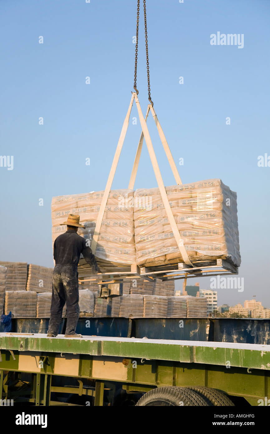 Importazione di materiali da costruzione, operai lo scarico dei pallet di cemento iraniano, consegnati da includersi in corrispondenza della banchina di Al Sharjah, Dubai, UAE Foto Stock