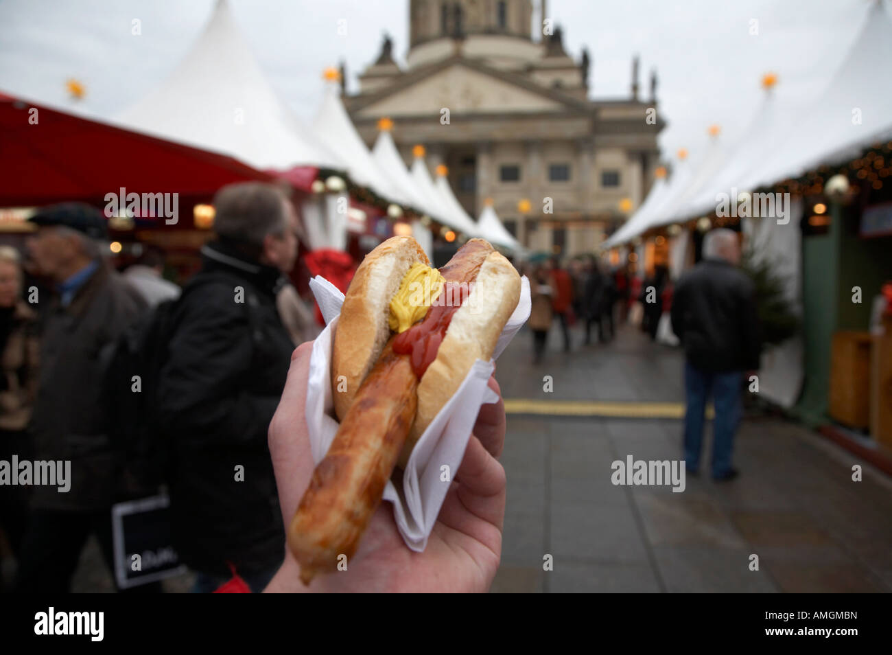 I turisti passeggiate intorno al Gendarmenmarkt mercatino di natale con un rostbratwurst con ketchup e senape Foto Stock