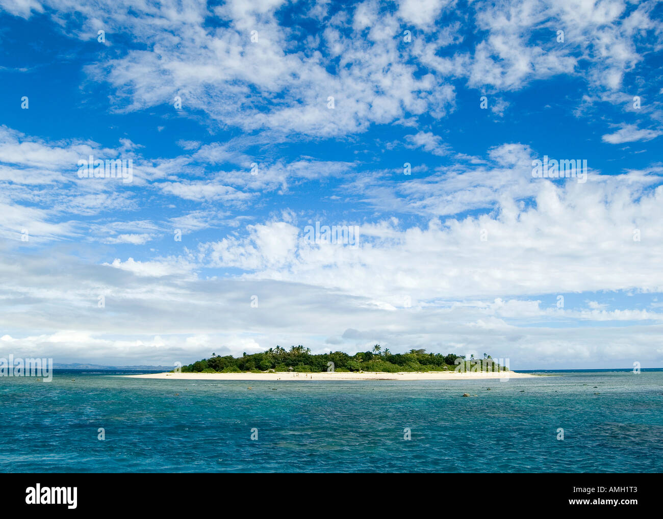 Malamala isola al largo della costa di Nadi nelle isole Figi, circondato da acque blu cristalline e luminoso cielo blu in una calda giornata estiva Foto Stock
