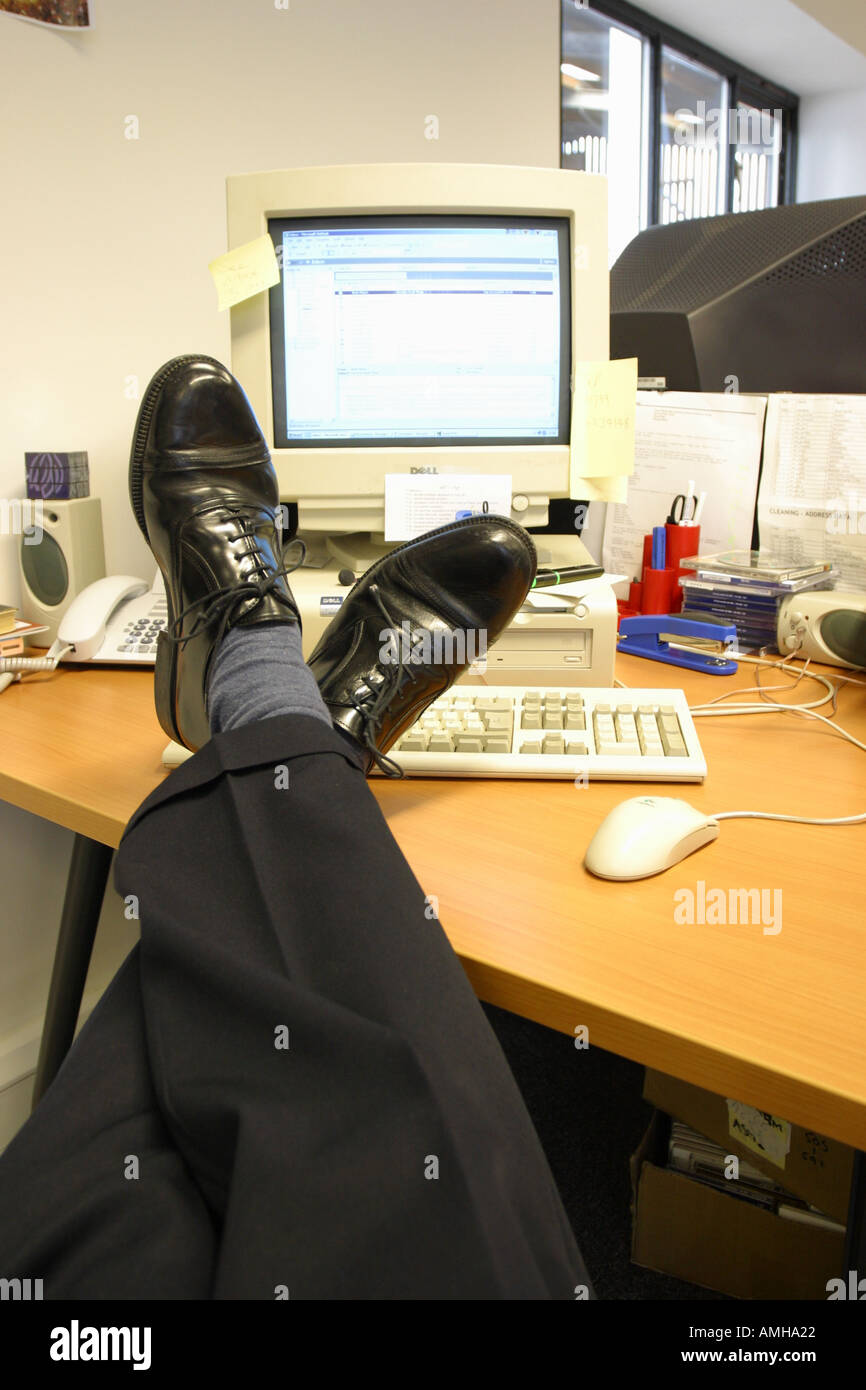 Lavoratore di ufficio con piedi tenendo rilassato è facile sul desktop durante il lavoro Foto Stock