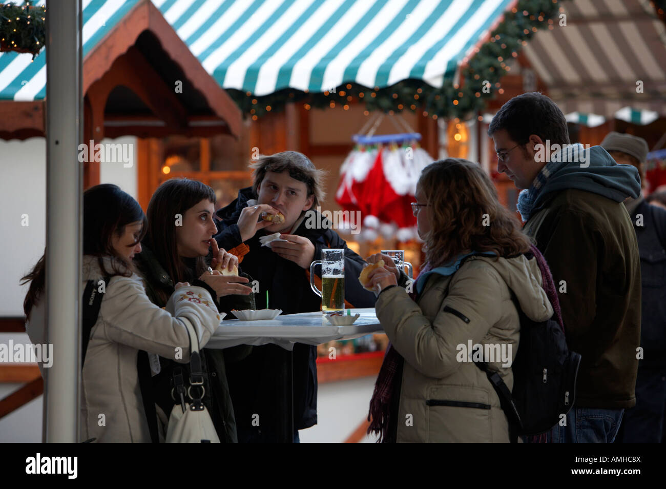 Il turista a godere di un pranzo snack a uno del cibo all'aperto si spegne ad Alexanderplatz mercatino di Natale Berlino Germania Foto Stock